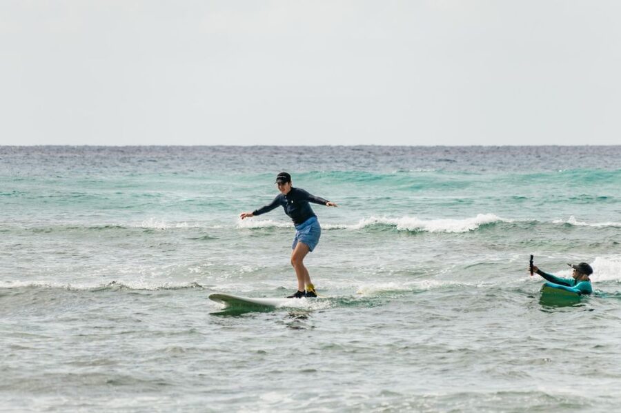 A surfer riding a small wave off Waikiki, palms on the beach behind
